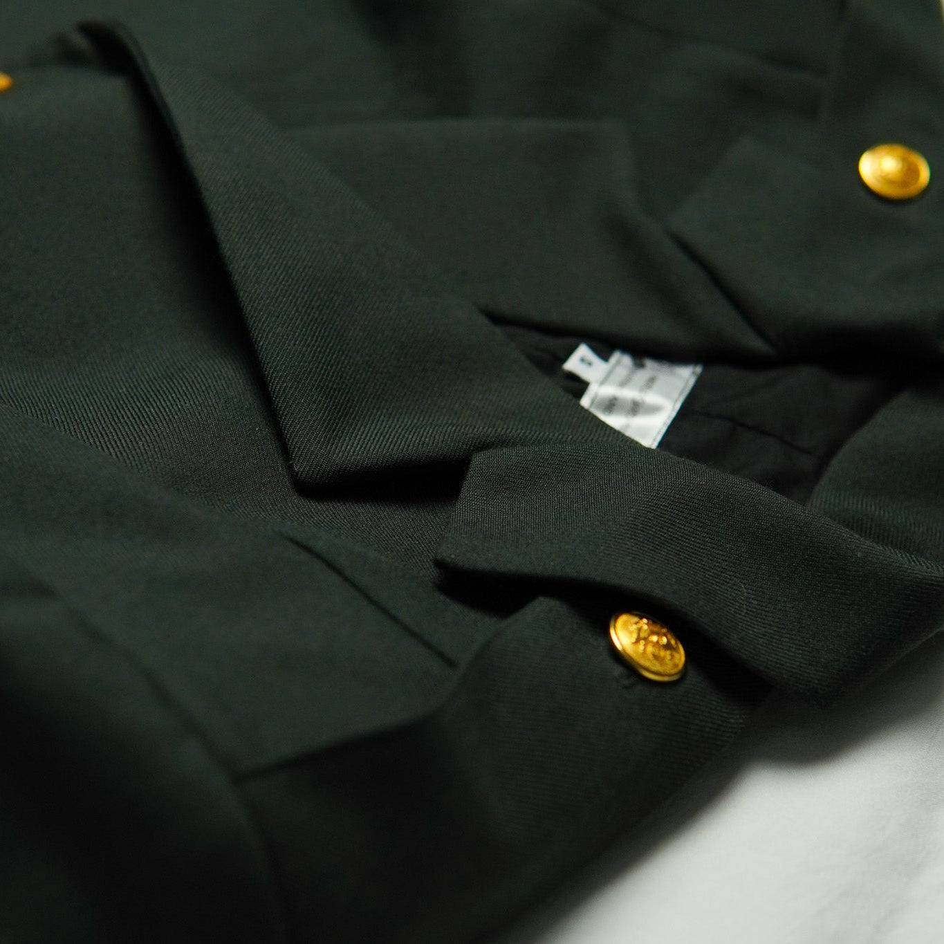 Dark green jacket with gold buttons on a light gray background