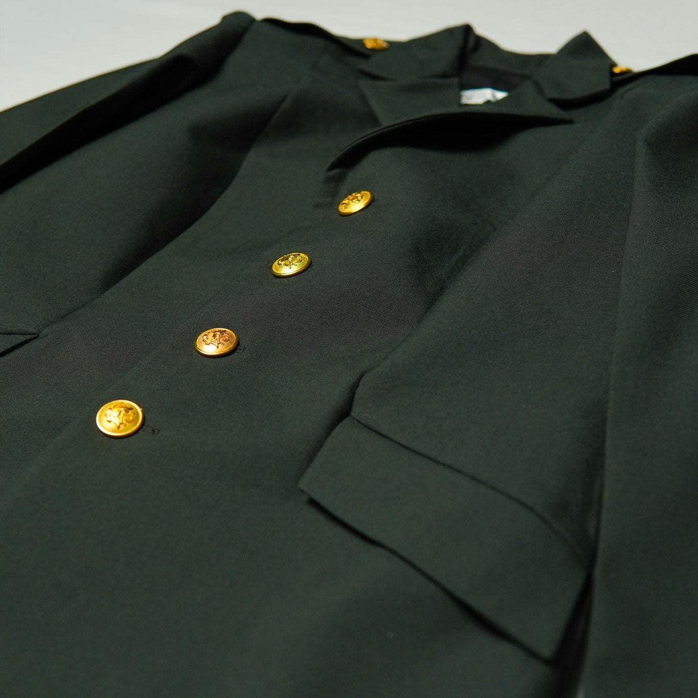 Dark green military-style jacket with gold buttons on a light gray background