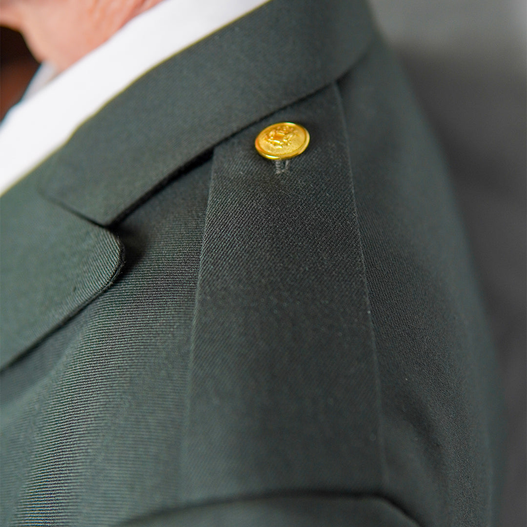 Green suit jacket with a gold button on a blurred background